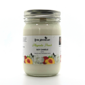 Photo of Byrd Apothecary Magnolia Peach Soy Candle with crackling Wooden Wick in a canning jar. The label background is a magnolia bloom and a cut open peach.