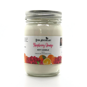 Photo of Byrd Apothecary Raspberry Orange Soy Candle with crackling Wooden Wick in a canning jar. The label background is a bunch of fresh red raspberries with whole and cut oranges.